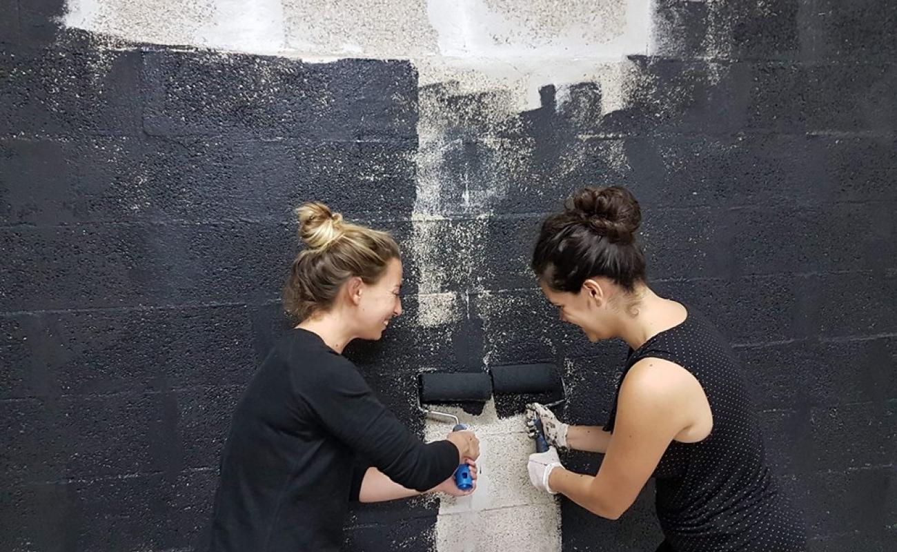 2 filles peignent un mur en noir